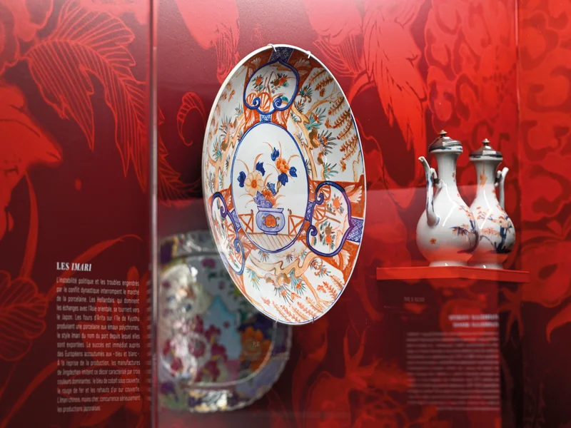 Vitrine d'exposition au MADOI présentant de la porcelaine chinoise délicate.