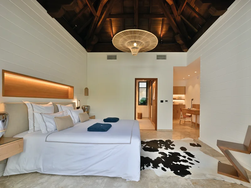 Chambre de villa avec charpente apparente et vue sur le jardin tropical